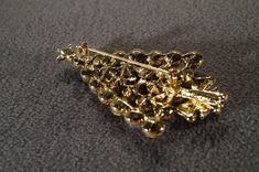 I am offering this fabulous vintage yellow gold tone brooch. This piece is truly gorgeous, and it has the following features: * vintage pin * rhinestone * glass stone * holiday theme * christmas tree * 2.5 inches in length This is a fantastic and classic piece. There is tons of sparkle and shine with this piece. It will beautifully complement your upcoming fashion season. Buyer pays all shipping and handling. Vintage Gold Jewelry For Christmas, Elegant Gold Brooches For Christmas, Elegant Gold Christmas Brooches, Gold Holiday Brooch Jewelry, Vintage Gold Jewelry For Holidays, Vintage Gold Pins For Party, Gold Brooches For Formal Christmas Occasion, Gold Rhinestone Party Pins, Gold Christmas Brooches For Formal Wear