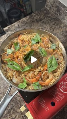 a pan filled with shrimp and rice on top of a stove