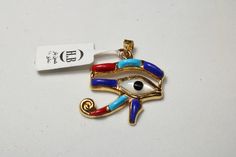 "Egyptian carving Handmade Colored Eye Of Horus 18K Yellow Gold Pendant 3.5 Gr Weight Approximate : 3.5 Gr Height : 1.2\" = 31 mm Width : 1\" = 27 mm ✔ IT IS Tested & SIGNED WITH THE EGYPTIAN Gold Government HALLMARK FOR 18K GOLD to Ensure Authenticity. ✔ Lovely gift idea ABSOLUTELY GORGEOUS, LOOKS FABULOUS ON. ✔ 100% Egyptian handmade. ✔ Condition: A brand-new, exactly as on the photos. ★ GIFTS ✔ All items are packaged in a paper jewelry gift box, ready for gifting. ✔ If you are sending a g Brass Evil Eye Jewelry As A Gift, Brass Evil Eye Jewelry For Gifts, Evil Eye Brass Jewelry As A Gift, Symbolic Pendant With Diamond Eyes, Gold Plated Evil Eye Symbolic Jewelry, Symbolic Gold Plated Evil Eye Jewelry, Gold Spiritual Jewelry With Evil Eye, Gold Amulet Jewelry With Diamond Eyes, Gold Plated Evil Eye Amulet Jewelry