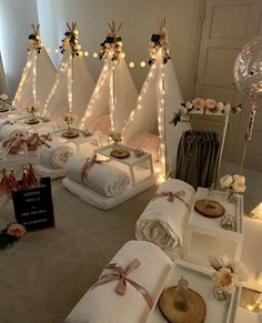 a room filled with lots of white blankets and pillows covered in lights next to candles