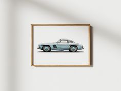 a framed photograph of an old car on a white wall with a wooden frame hanging above it