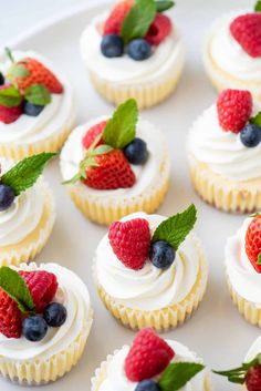 small cupcakes with white frosting and fresh berries on top are ready to be eaten