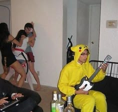 a man in a pikachu costume plays the guitar while people dance around him