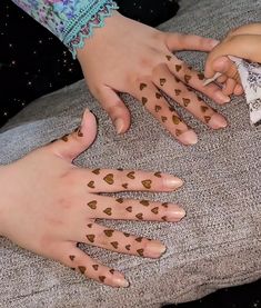 two hands with brown hearts painted on them and one hand is holding a white object