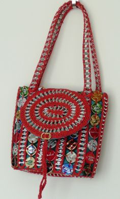 a red purse hanging from the side of a white wall with buttons and beads on it