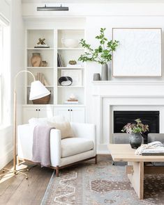 a living room with white furniture and a fireplace