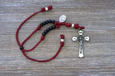 Looking for a powerful yet compact rosary to bring the intercession of St. Maximilian Kolbe into your daily travels? Look no further than our Militia Immaculatae - St. Maximilian Kolbe Rearview Mirror Paracord Rosary. This stunning red paracord rosary, measuring approximately 9 inches when tightened and expanding up to 13 inches for easy installation on any rearview mirror, features 10 shiny black Hail Mary beads, a single silver Our Father bead, and a large 3-inch white enamel St. Benedict crucifix symbolizing the crowns received by this saintly hero of faith - one in martyrdom, and another in priesthood. Complete with a St. Kolbe devotional medal and an easy-to-use expansion mechanism, this rosary is a powerful reminder of the level of heroic virtue we must all aim to attain, as St. Kolb St Maximilian Kolbe, Maximilian Kolbe, Car Rosary, St Maximilian, Paracord Rosary, Catholic Family, Praying The Rosary, Hail Mary, 550 Paracord