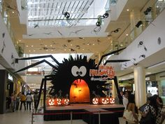 an indoor halloween display in a mall with pumpkins on the floor and decorations hanging from the ceiling