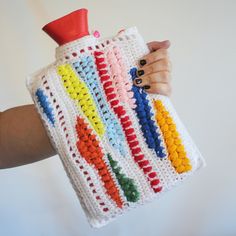 a person holding a crocheted water bottle cover in front of a white background