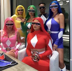 four women dressed in costumes posing for a photo with one woman wearing blindfolds