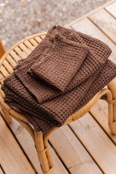 a stack of brown knitted blankets sitting on top of a wooden chair