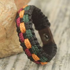 a multicolored bracelet sitting next to a rock