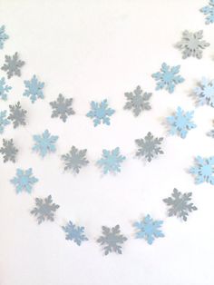 blue snowflakes are hanging from a string on a white wall with other decorations