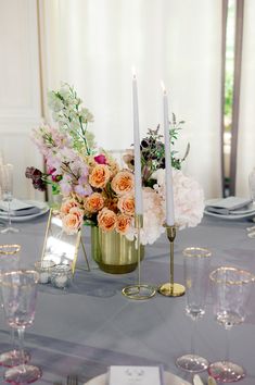 a centerpiece with flowers and candles on a table