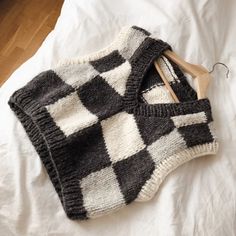 a black and white sweater laying on top of a bed next to a wooden hanger