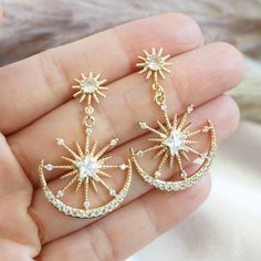 "This gold statement earrings feature double star burst design with a smaller starburst posts attached to a sparkly larger sunburst charm nestled in a crescent moon.  A unique large celestial earrings perfect for going out or whenever you want an extra pop of sparkle. DIMENSION: ----------------- Earrings : 1 inch wide x 1.5 inch long For other celestial jewelry, click here : https://www.etsy.com/shop/YsmDesigns?ref=seller-platform-mcnav&search_query=celestial PACKAGING/ GIFTING: --------------- Gold Star Jewelry Aesthetic, Gold Celestial Jewelry, Gold Star-shaped Crystal Earrings For Pierced Ears, Gold Star-shaped Celestial Earrings, Gold Starburst Celestial Earrings, Gold Celestial Star Earrings, Celestial Packaging, Celestial Earrings, Earrings Double