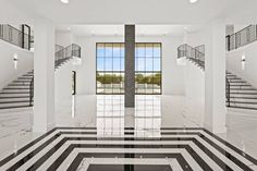 an empty room with black and white stripes on the floor, stairs to the second floor