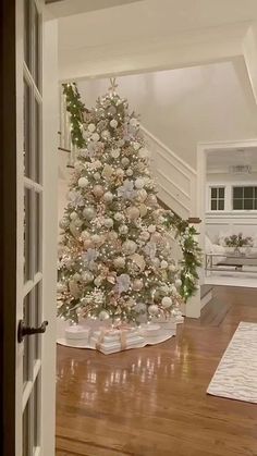 a decorated christmas tree sitting in the middle of a living room next to a doorway