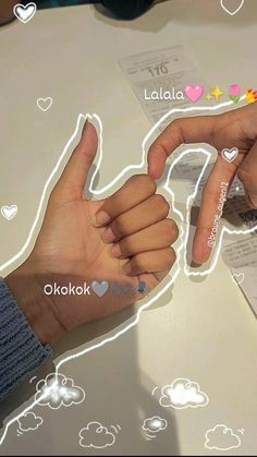 two hands are pointing at each other with hearts and clouds on the table behind them