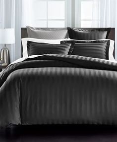 a bed with black and white striped comforter in a room next to a window