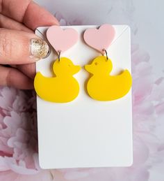 a pair of yellow rubber ducky earrings with pink hearts