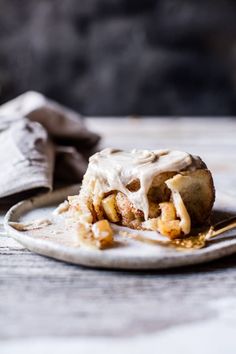 a piece of food on a plate with a fork and napkin next to it, sitting on a table