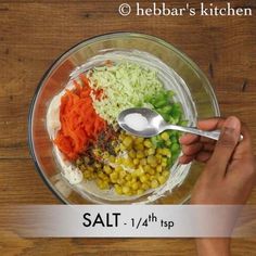 a person holding a spoon over a bowl filled with vegetables