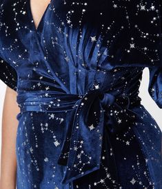 Wrap yourself in stars, dears! This sensational 1970s style wrap dress from Unique Vintage is crafted in a gorgeous navy blue velvet that dances with twinkling silver stars throughout. The sultry wrap design is secured with dual buttons creating a surplice neckline that is framed by dolman sleeves. The seamed high waist is cinched by a matching self tie sash while the skirt cascades to a sweeping midi silhouette!Available in sizes XS-5X while supplies last. Holiday Cocktail Dress Plus Size, Blue 1920s Dress, Feyre Dress, 70s Dresses Formal, Dune Fashion, Celestial Outfit, Celestial Gown, Dark Blue Velvet Dress, Fashion Definition