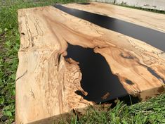 a piece of wood that is laying on the ground with grass in front of it