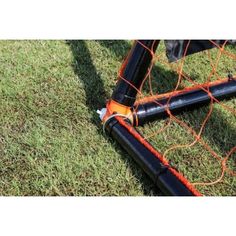 an orange soccer goal on the grass with two poles sticking out of it's net