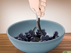 a bowl filled with blueberries being spooned into it by someone's hand