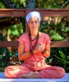 a woman sitting in a lotus position with her hands clasped to her chest and eyes closed