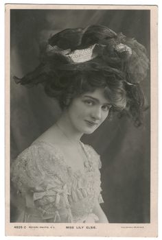 an old black and white photo of a woman wearing a hat with feathers on it