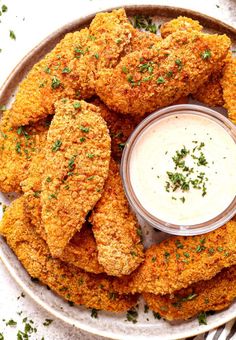 some fried food is on a plate with a small bowl of ranch dressing next to it