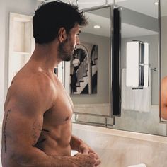 a shirtless man standing in front of a bathroom mirror looking at himself in the mirror