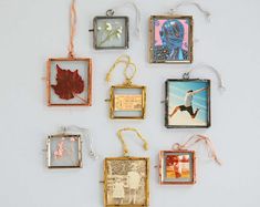 six framed pictures hanging from strings on a white wall next to a maple leaf and an ornament