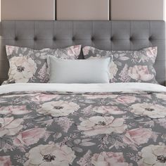 a bed with floral comforter and pillows on top of it in front of a headboard