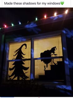 the silhouettes of two trees are projected in front of an open window at night