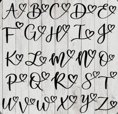 the letters are handwritten in black ink on white wooden planks, with hearts and arrows