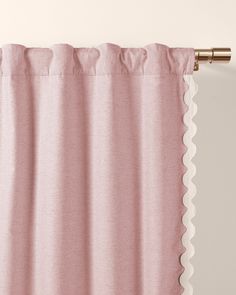 a pink curtain with scalloped edges hanging on a wall