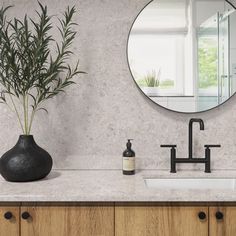 a bathroom sink with a black vase on it and a round mirror above the sink