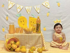 a baby sitting in front of a table filled with lemons