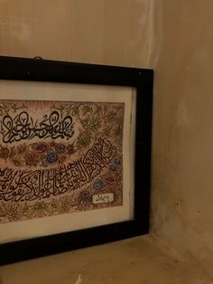 a framed islamic calligraphy displayed on a wall