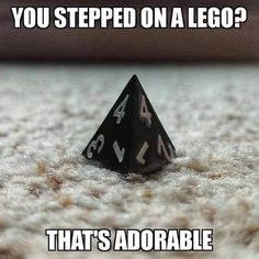 a black dice sitting on top of a white carpet next to the words you stepped on a lego? that's adorable