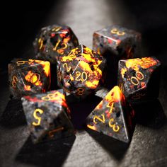 a set of black and orange dice with gold numbers on each side, sitting on a table