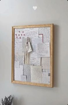 a wall with many pieces of paper attached to it and a heart hanging on the wall