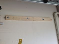 there is a piece of wood hanging on the wall next to some wires and a light fixture