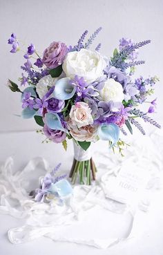 a bouquet of flowers sitting on top of a white sheet covered tablecloth next to a card