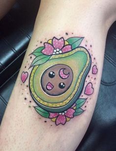 an avocado tattoo on the leg with hearts and flowers around it's eyes