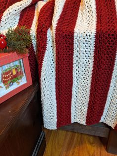 a red and white blanket sitting on top of a bed next to a wooden dresser